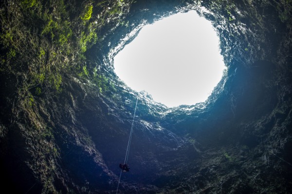 Salah satu aggota tim menuruni entrance vertikal Luweng Ombo pada seutas tali menggunakan Single Rope Technique