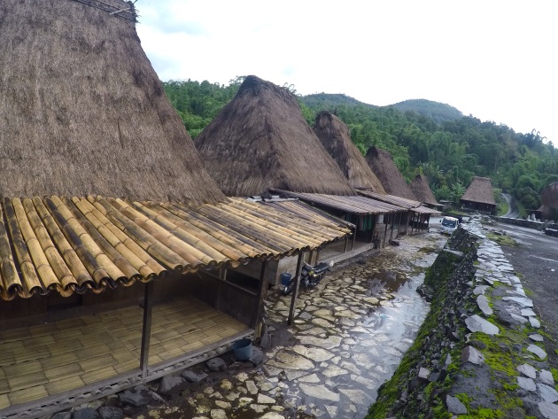 Dengan bangunan rumah yang didominasi tumpukan bambu pada alas rumah dan dinding, atap berlapis alang-alang, lalu bebatuan pada jalan dan tangganya.