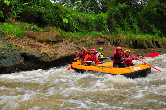 Sebuah perahu terlihat sedang dalam posisi yang tidak normal ketika berada di atas jeram. Skippernya, Adit, berusaha membetulkan posisi perahu dengan sekuat tenaga.